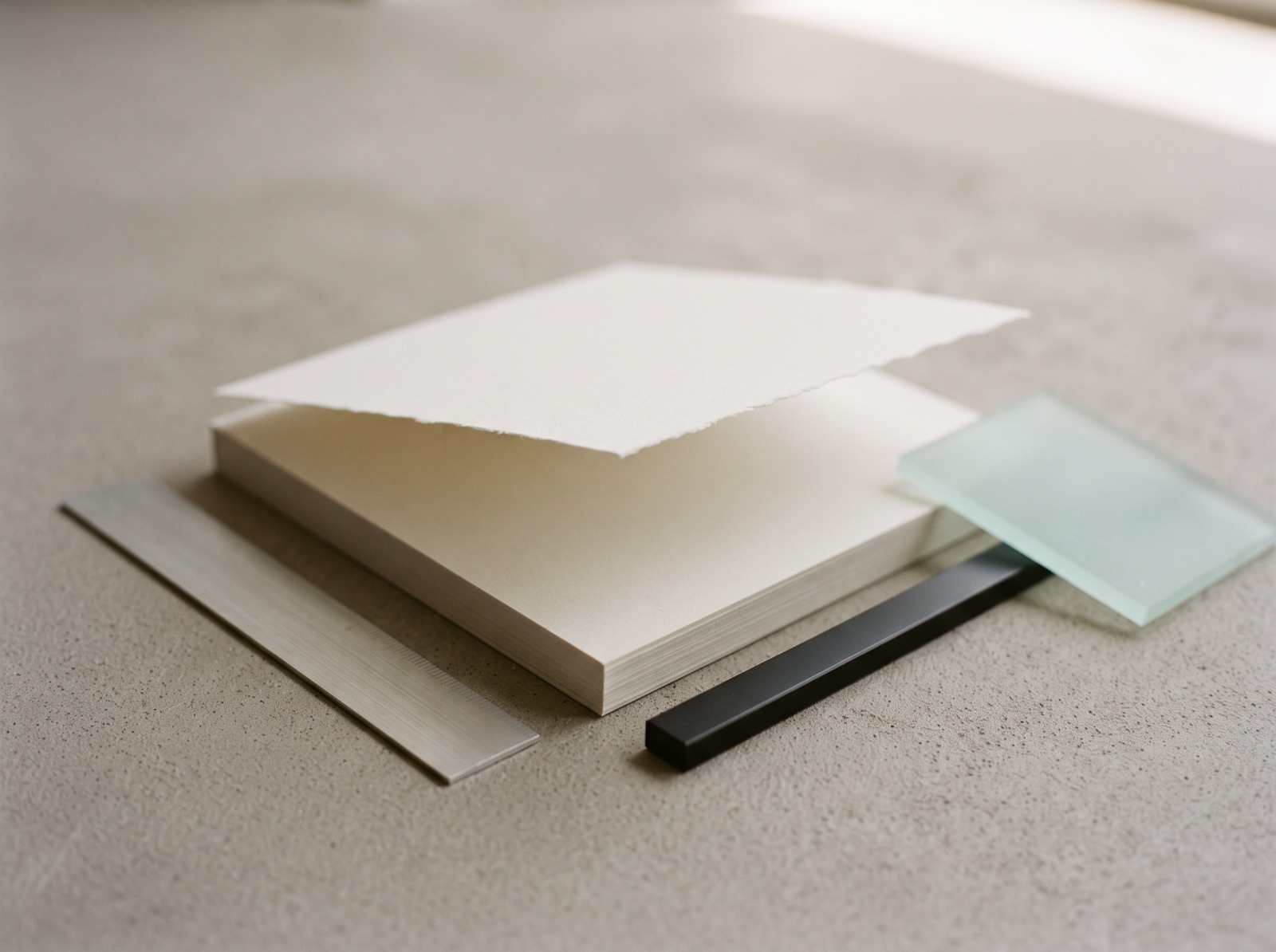 Ein gerader Papierstapel, ein Blatt angehoben, daneben Lineal und Glas