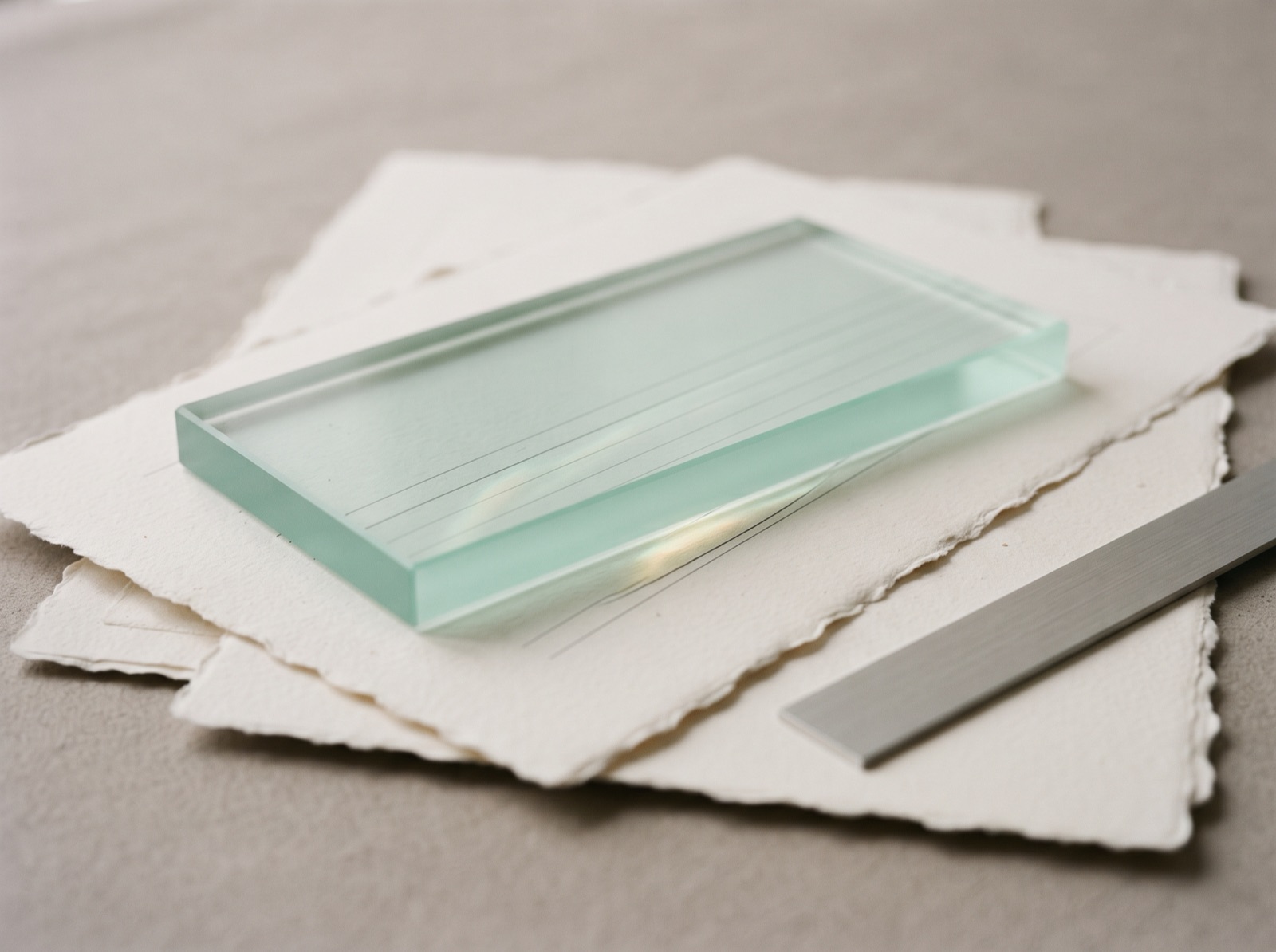 Papierbögen unter einer Scheibe aus mattem Glas, darunter feine Linien